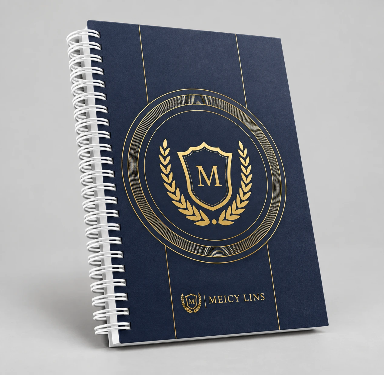 Caderno Meicy Lins com capa azul escura, detalhes dourados e encadernação wire-o branca.